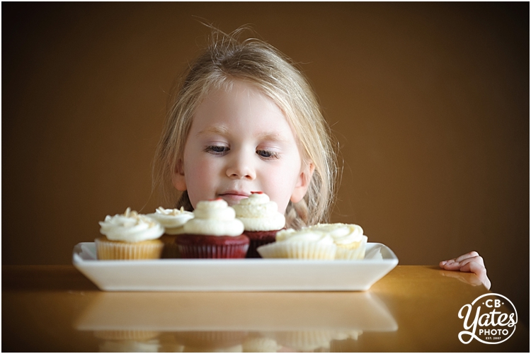 Child gazing over plate of decorated cupcakes