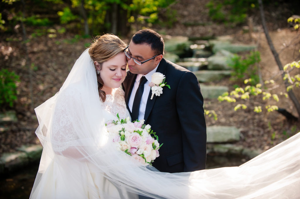 Bride and Groom in Lauritzen Gardens snuggling for Wedding Photography cb Yates